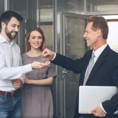 Agent przekazuje klucze parze młodych ludzi w biurze.