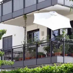 Nowoczesny balkon z roślinami i białym parasolem. Czy balkon wlicza się do powierzchni użytkowej mieszkania?