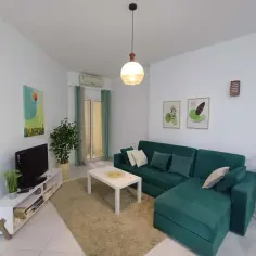 Nowoczesny salon z zieloną kanapą i białym stolikiem. Zastanawiasz się, ile kosztuje wynajem mieszkania w Egipcie?