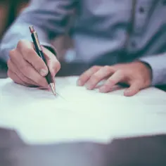 Dłoń pisze na papierze, być może to instrukcja, jak wykreślić hipotekę przymusową.