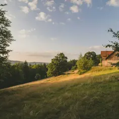 Słoneczna polana z domkiem na wzgórzu, otoczona lasem. Idealne miejsce na budowę domu, zastanawiasz się, ile za ar działki budowlanej?
