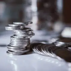 Stos monet symbolizuje finanse, zastanawiamy się, kto płaci podatek od dzierżawy gruntu.