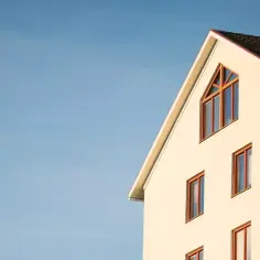 Jasny budynek z oknami na tle błękitnego nieba. Jak sprawdzić dewelopera przed zakupem mieszkania?