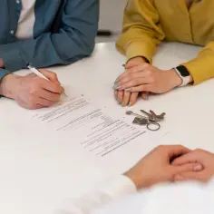Podpisanie umowy najmu, klucze na stole. Czy kaucję za mieszkanie płaci się co miesiąc?