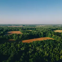 Krajobraz z lotu ptaka, ukazujący lasy i pola uprawne. Widok idealny do analizy na geoportal powiatu siedleckiego.