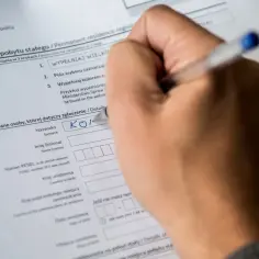Ręka wypełnia formularz "Zgłoszenie pobytu stałego". Czy w mieszkaniu musi być ktoś zameldowany? To pytanie często pojawia się przy wypełnianiu takich dokumentów.