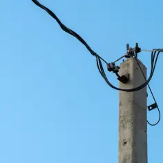 Betonowy słup energetyczny z kablami. Zastanawiasz się, ile odszkodowania za słup energetyczny na działce?