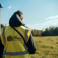 Geodeta w kamizelce odblaskowej z odbiornikiem GPS. Dowiedz się, jak znaleźć granice działki telefonem, korzystając z nowoczesnych technologii.