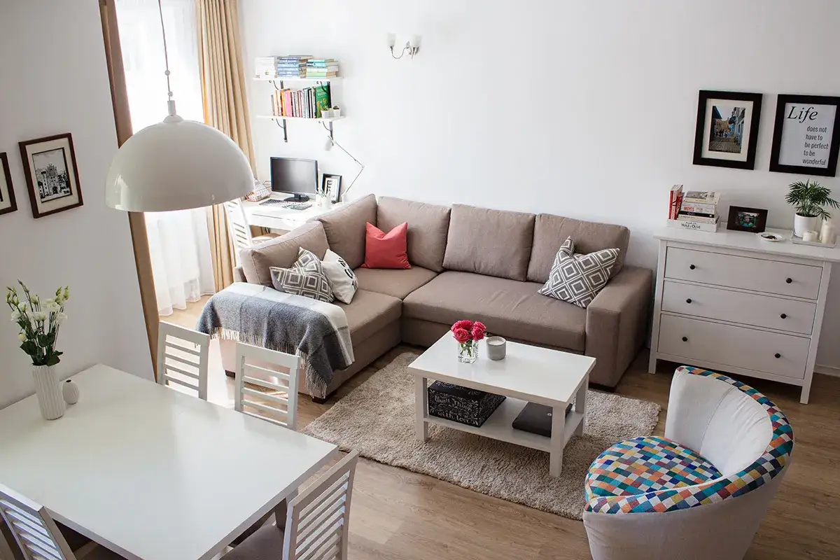Przytulny salon z sofą, stolikiem kawowym i jadalnią. Inspiracja, jak odkładać pieniądze na mieszkanie, zaczyna się od organizacji przestrzeni.