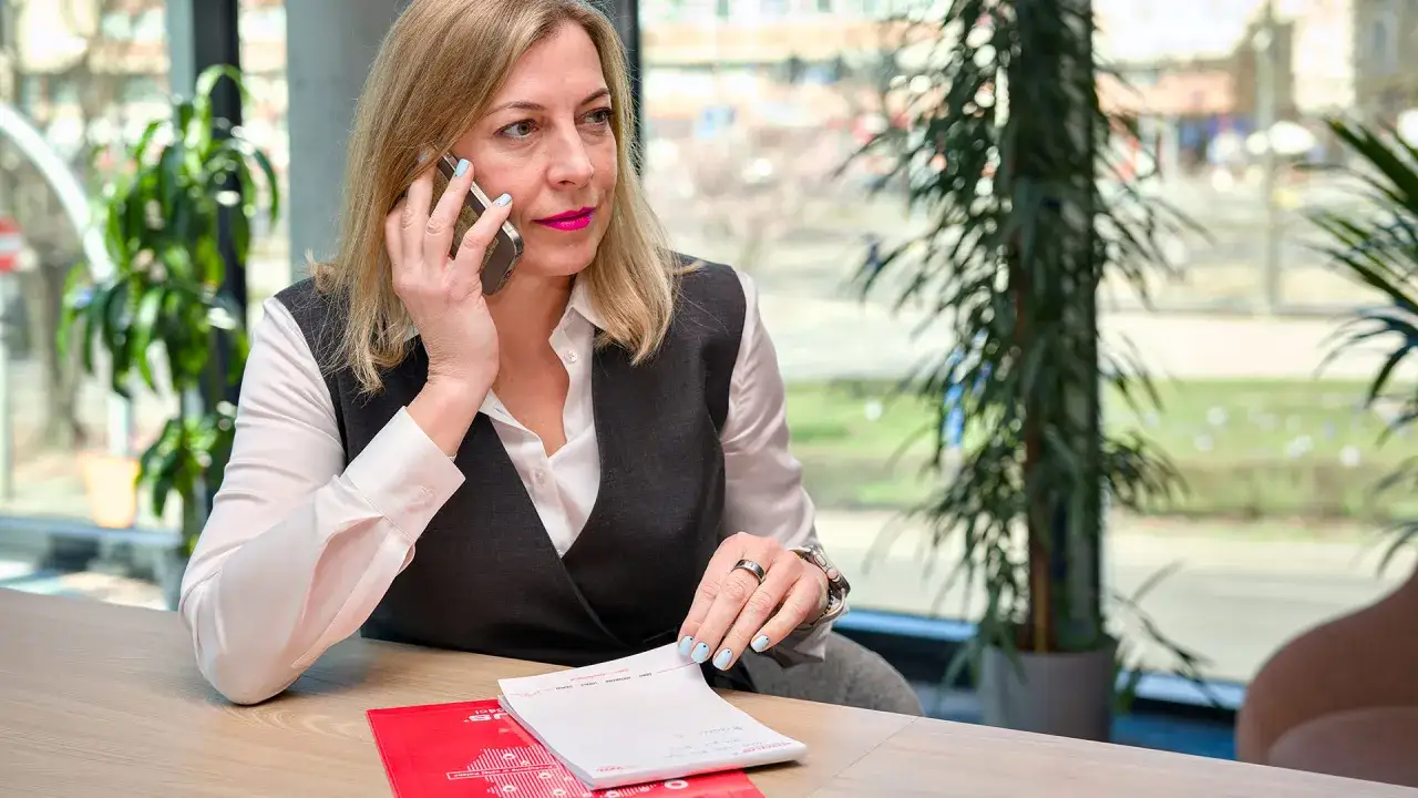 Pośrednik nieruchomości rozmawia przez telefon, notując ważne informacje.