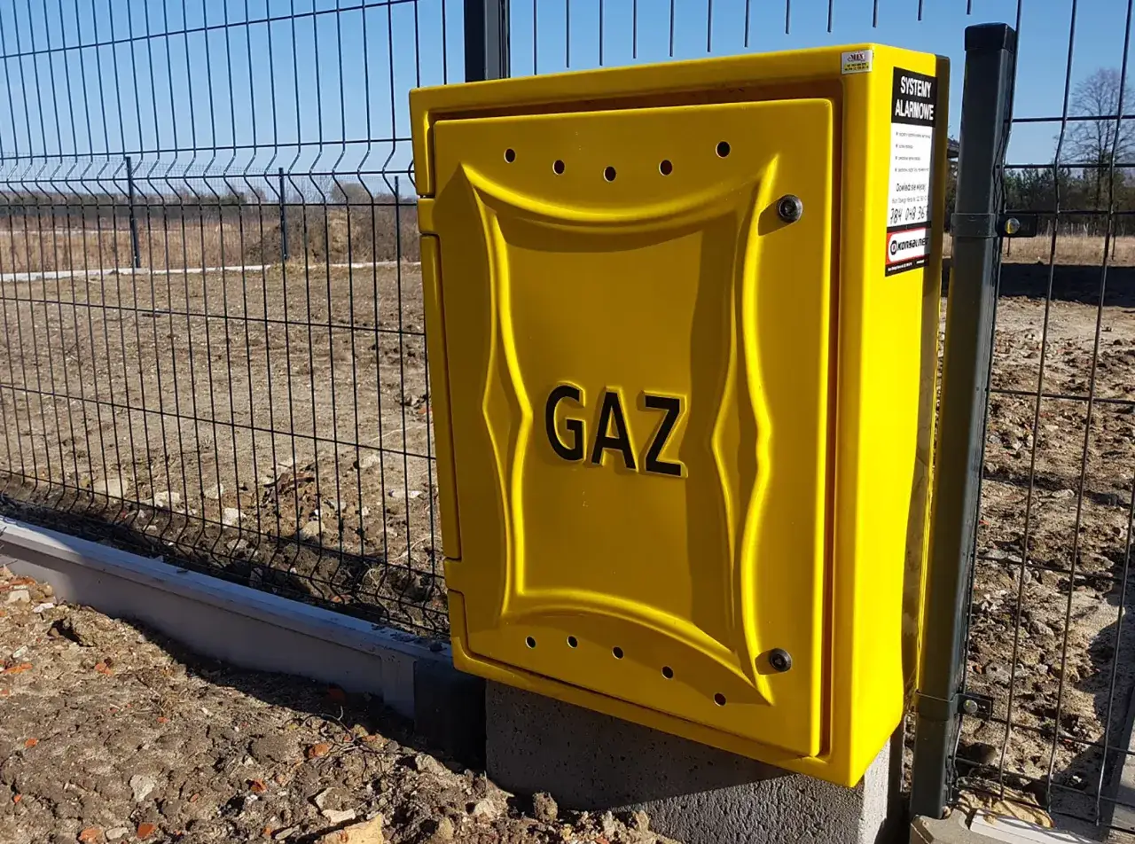 Żółta skrzynka gazowa przy ogrodzeniu. Zastanawiasz się, ile kosztuje przyłącze gazowe?