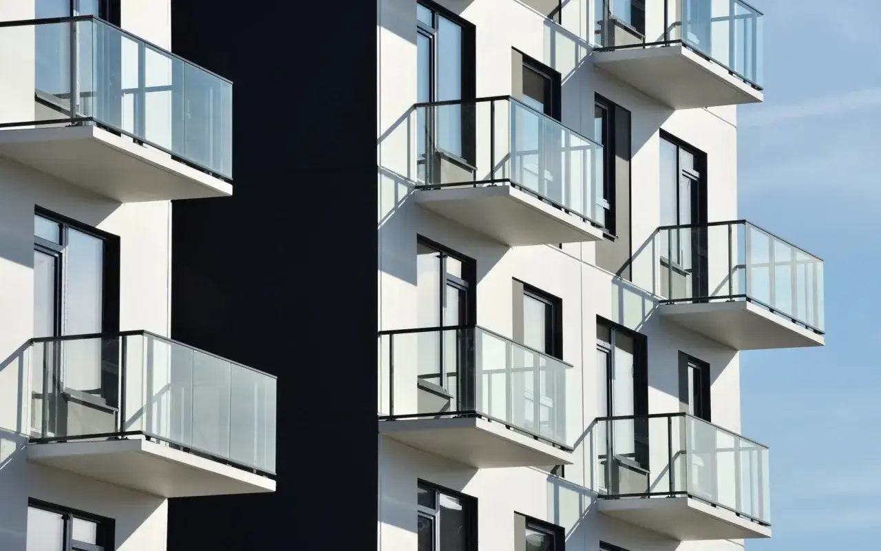 Nowoczesny budynek z białymi balkonami i szklanymi balustradami. Zastanawiasz się, czy balkon wlicza się do metrażu mieszkania?