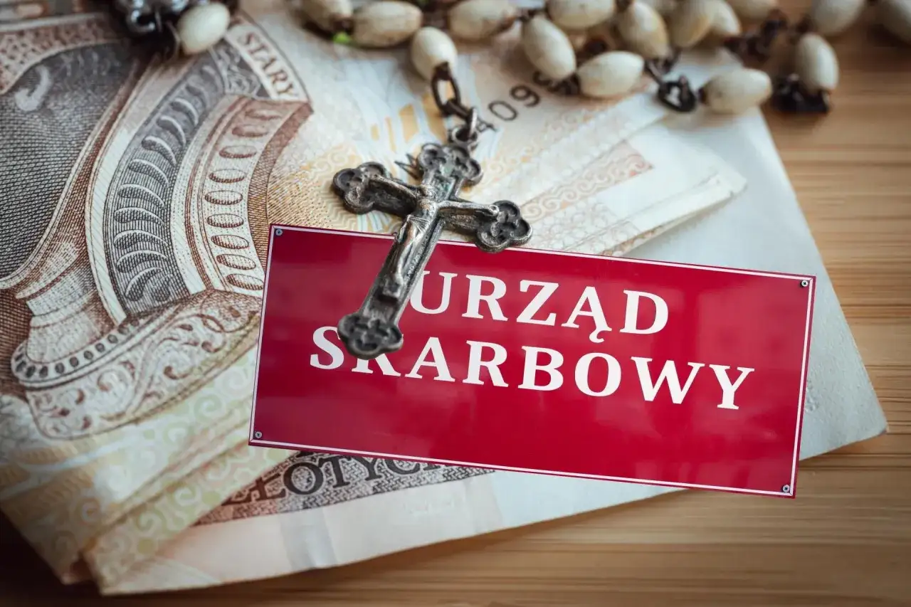 Krzyż i pieniądze na tle tabliczki