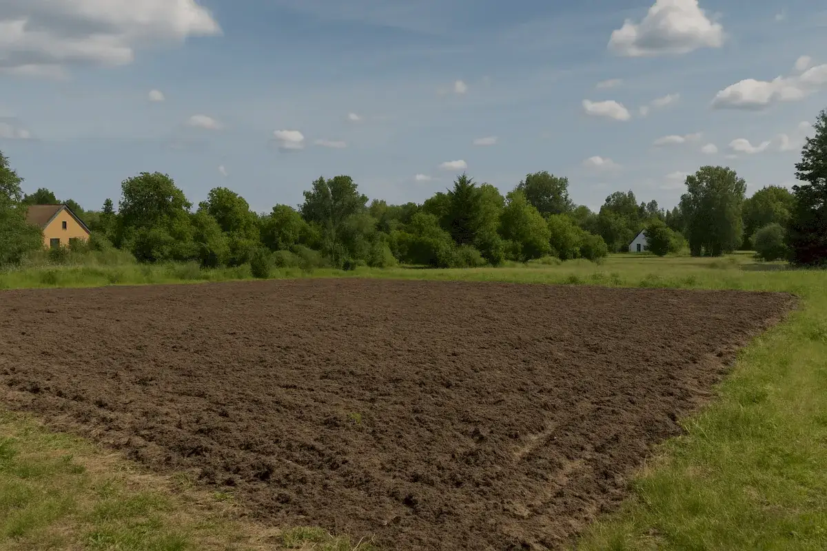 Przekopana ziemia na polu, domki w tle. Zastanawiasz się, ile czasu trwa odrolnienie działki?