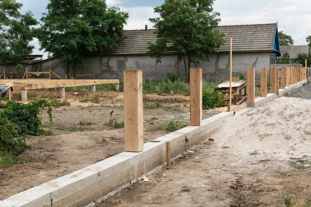 Budowa ogrodzenia i fundamentów domu. Drewniane słupki wyznaczają teren, pokazując, jak wyznaczyć granice działki samemu.