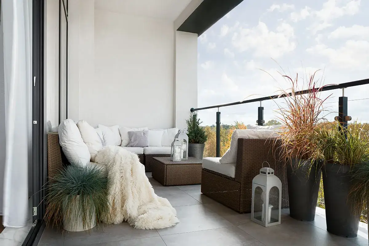 Przytulny balkon z meblami rattanowymi i kocykiem. Zastanawiasz się, czy balkon wlicza się do metrażu mieszkania?