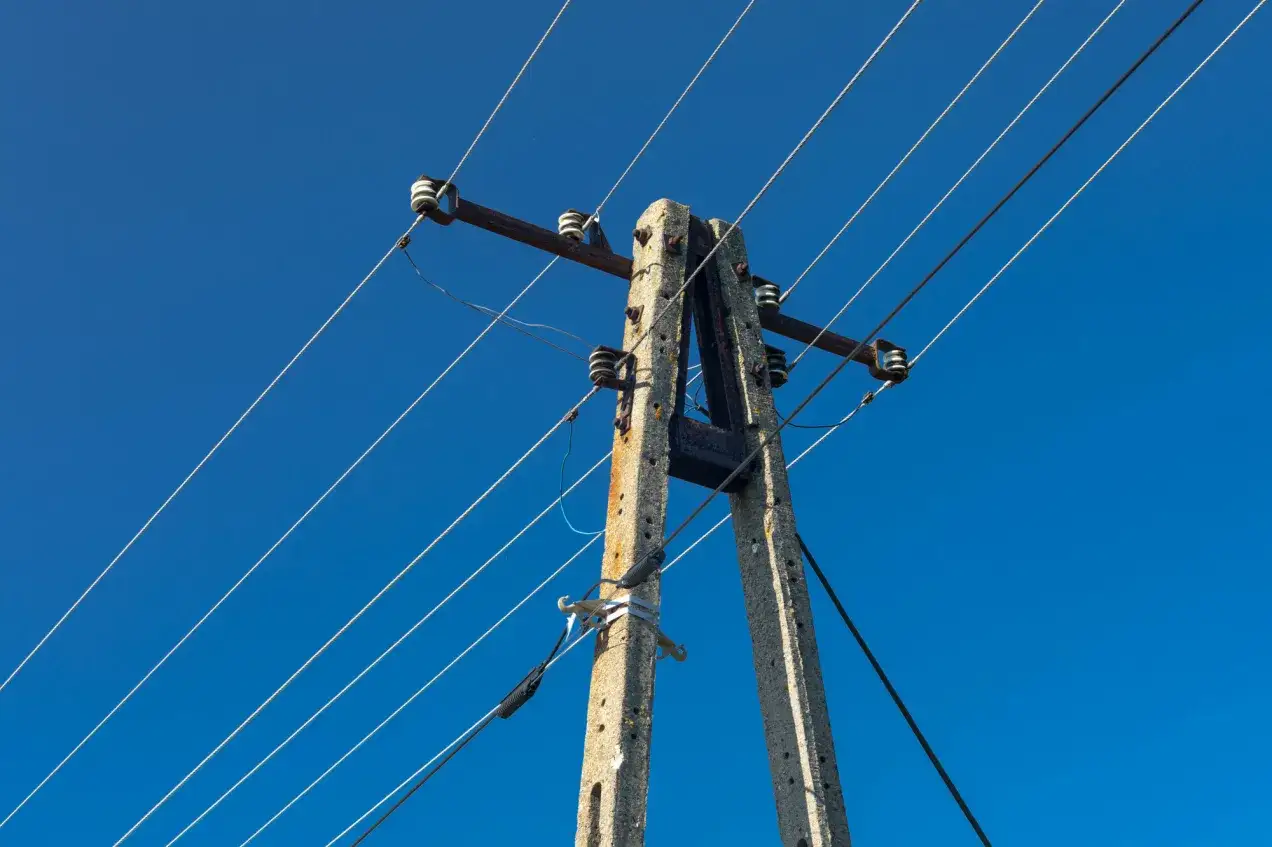 Słupy energetyczne na tle błękitnego nieba. Zastanawiasz się, ile można dostać odszkodowania za słupy energetyczne?