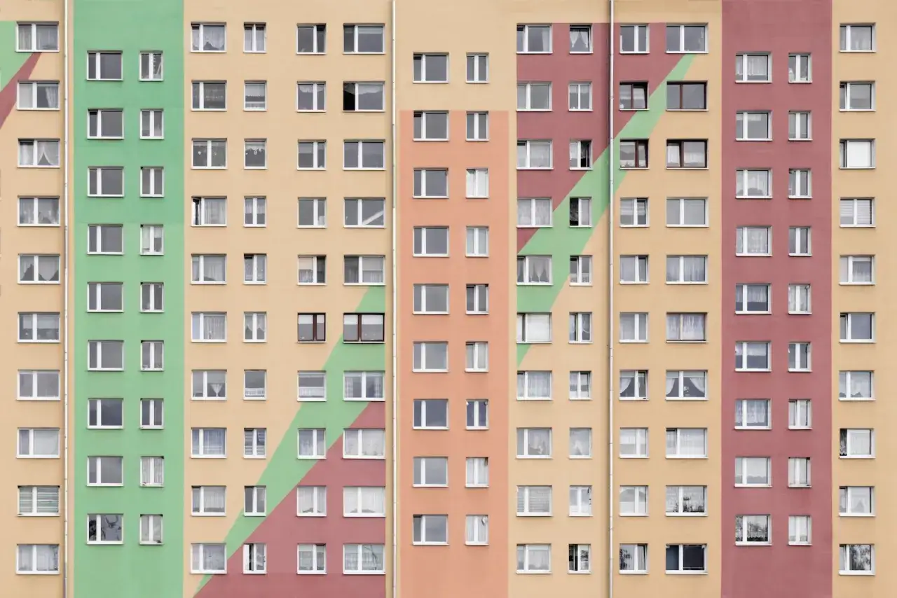Wielopiętrowy blok z kolorowymi pasami. Szukasz informacji, jak obliczyć dochód do mieszkania komunalnego?