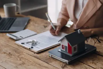 Klucze do domu, dokumenty i model domu na biurku. Dowiedz się, gdzie uzyskać akt własności domu, aby sfinalizować transakcję.